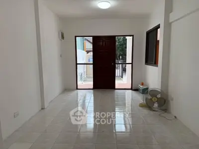 Spacious empty room with tiled floor and large window, ideal for customization.