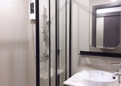 Modern bathroom with glass shower enclosure and sleek basin, featuring neutral tones and clean lines for a minimalist aesthetic.