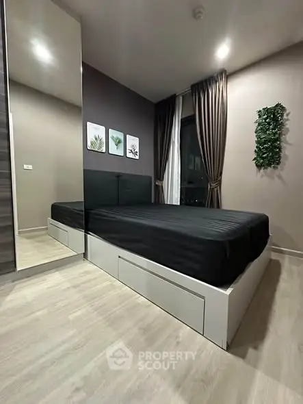 Modern bedroom with sleek design, featuring a black bed, large mirror, and stylish decor.