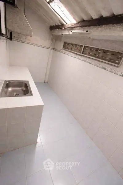 Compact kitchen space with tiled walls and a single sink, ideal for efficient cooking in small apartments.