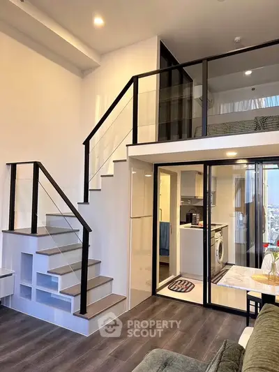 Modern loft apartment with stylish staircase and glass railing, featuring a cozy living area and city view.