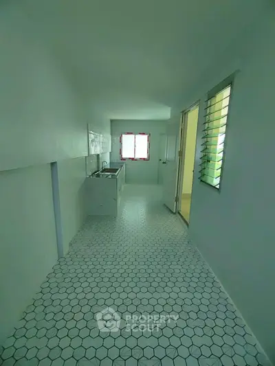 Compact kitchen with hexagonal tile flooring and natural light