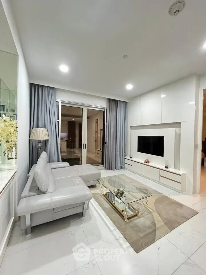 Modern living room with sleek white furniture and glass coffee table