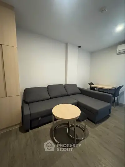 Modern living room with sleek gray sofa and stylish round coffee table in a cozy apartment.