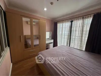 Cozy bedroom with large window and wooden furniture, perfect for relaxation.