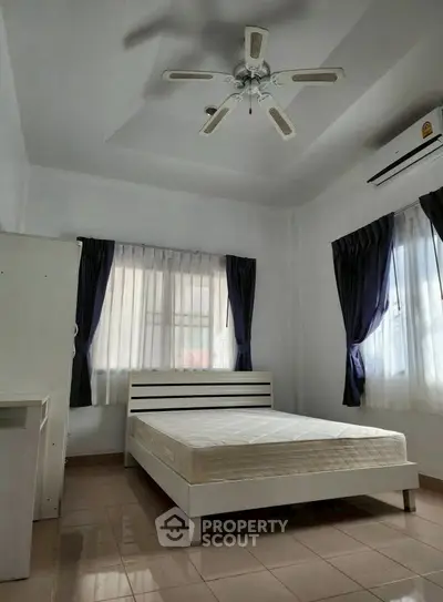 Spacious bedroom with ceiling fan and natural light, perfect for comfort and relaxation.