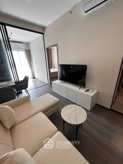 Modern living room with sleek furniture and natural light, featuring a cozy sofa and flat-screen TV.