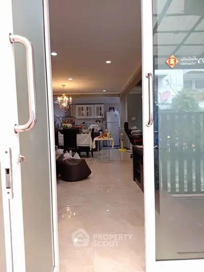 Spacious open-plan living and dining area with elegant chandelier and modern kitchen.