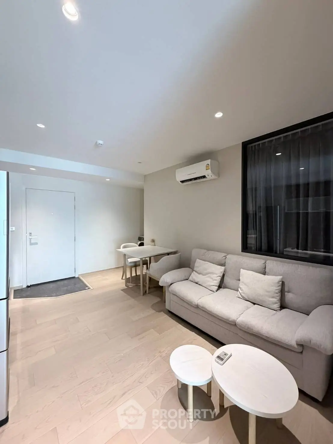Modern living room with cozy sofa, air conditioning, and stylish dining area in open layout apartment.