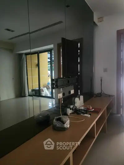 Modern interior with sleek mirrored wall and wooden console in a stylish living space.