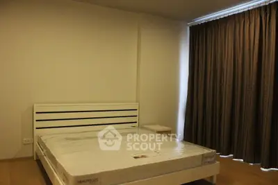 Spacious bedroom with modern bed and large window with curtains, perfect for relaxation.