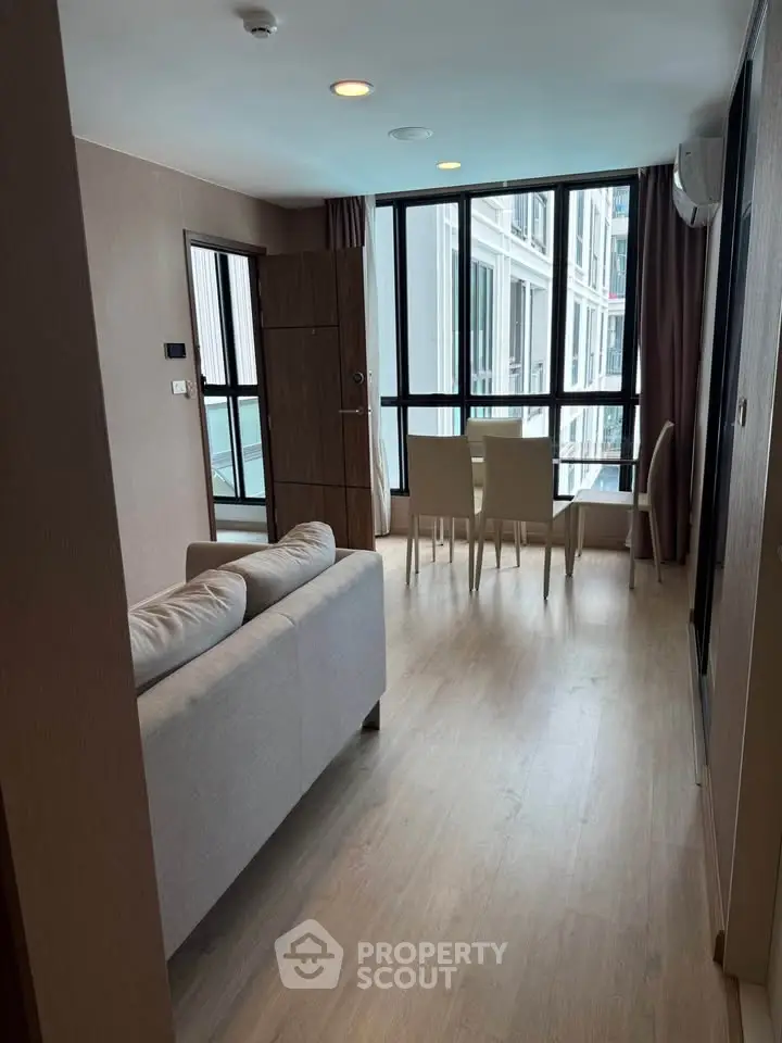Modern living room with large windows and dining area in a stylish apartment.