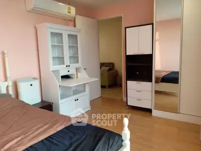 Spacious bedroom with modern furniture and mirrored wardrobe in a cozy apartment.
