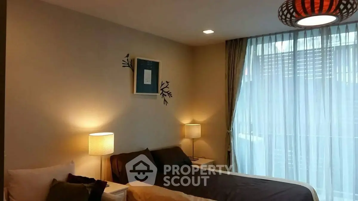 Cozy bedroom with soft lighting and elegant decor, featuring a large window with sheer curtains.