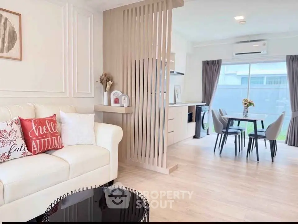 Modern living room with elegant decor and open dining area, featuring cozy seating and stylish furnishings.