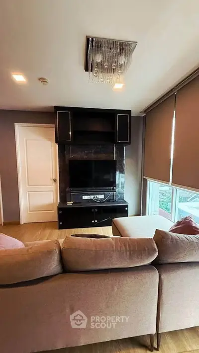 Modern living room with stylish sofa and entertainment center, featuring elegant lighting and large windows.