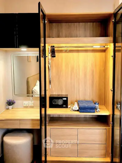 Modern bedroom with stylish wardrobe and vanity area, featuring a safe and neatly arranged towels.