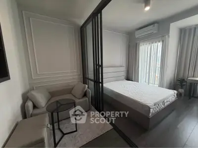 Modern studio apartment with glass partition and cozy furnishings.