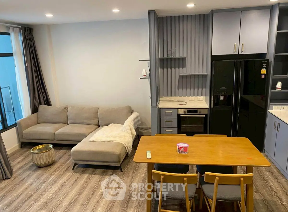 Modern living room with open kitchen, featuring sleek furniture and stylish decor.