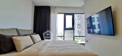 Modern bedroom with large window and wall-mounted TV in urban apartment