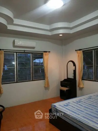Spacious bedroom with large windows and modern ceiling design, featuring a comfortable bed and air conditioning.