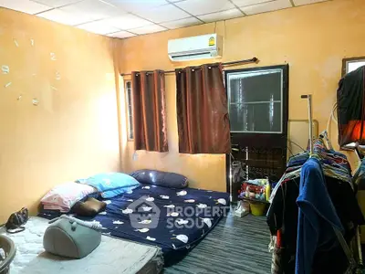 Cozy bedroom with air conditioning and natural light, featuring a simple bed setup and clothes rack.