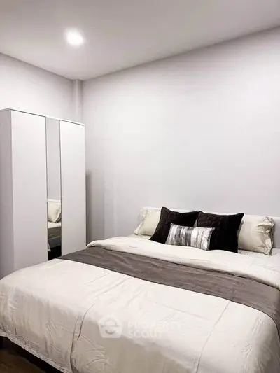 Cozy bedroom with elegant bedding and modern wardrobe in a serene setting.