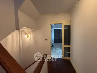Elegant hallway with wooden staircase and sliding door leading to a bright room.