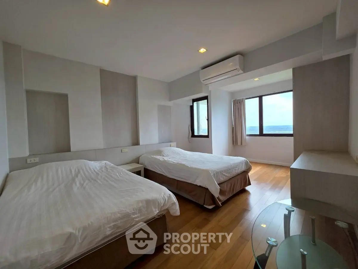 Spacious bedroom with two beds and ocean view, featuring modern decor and natural light.