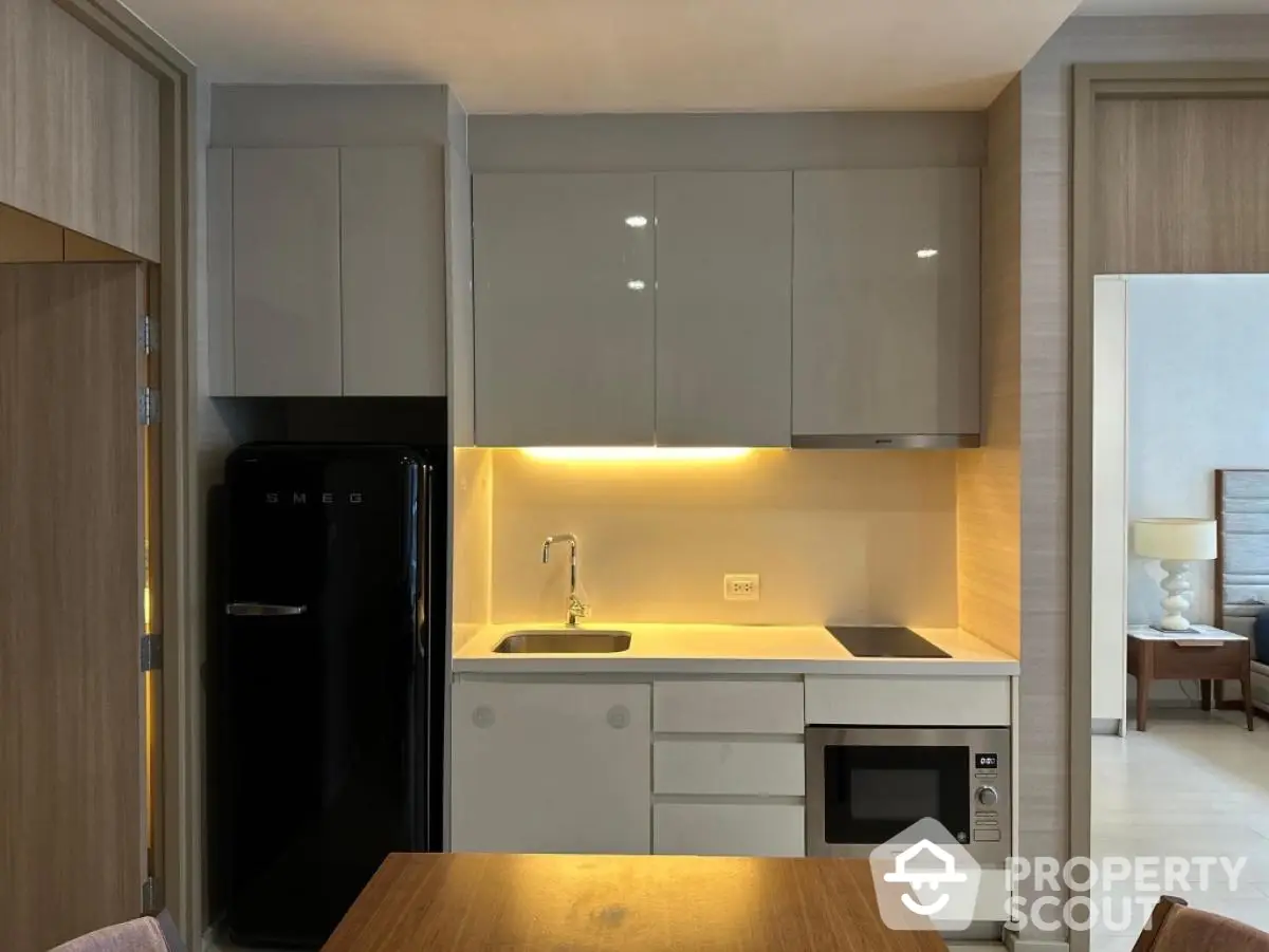 Modern kitchen with sleek cabinetry, built-in appliances, and cozy dining area in stylish apartment.