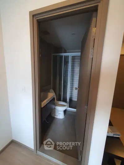 Compact modern bathroom with shower and toilet in sleek design.