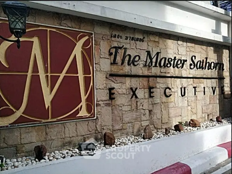 The Master Sathorn Executive building entrance sign with elegant stone wall design.