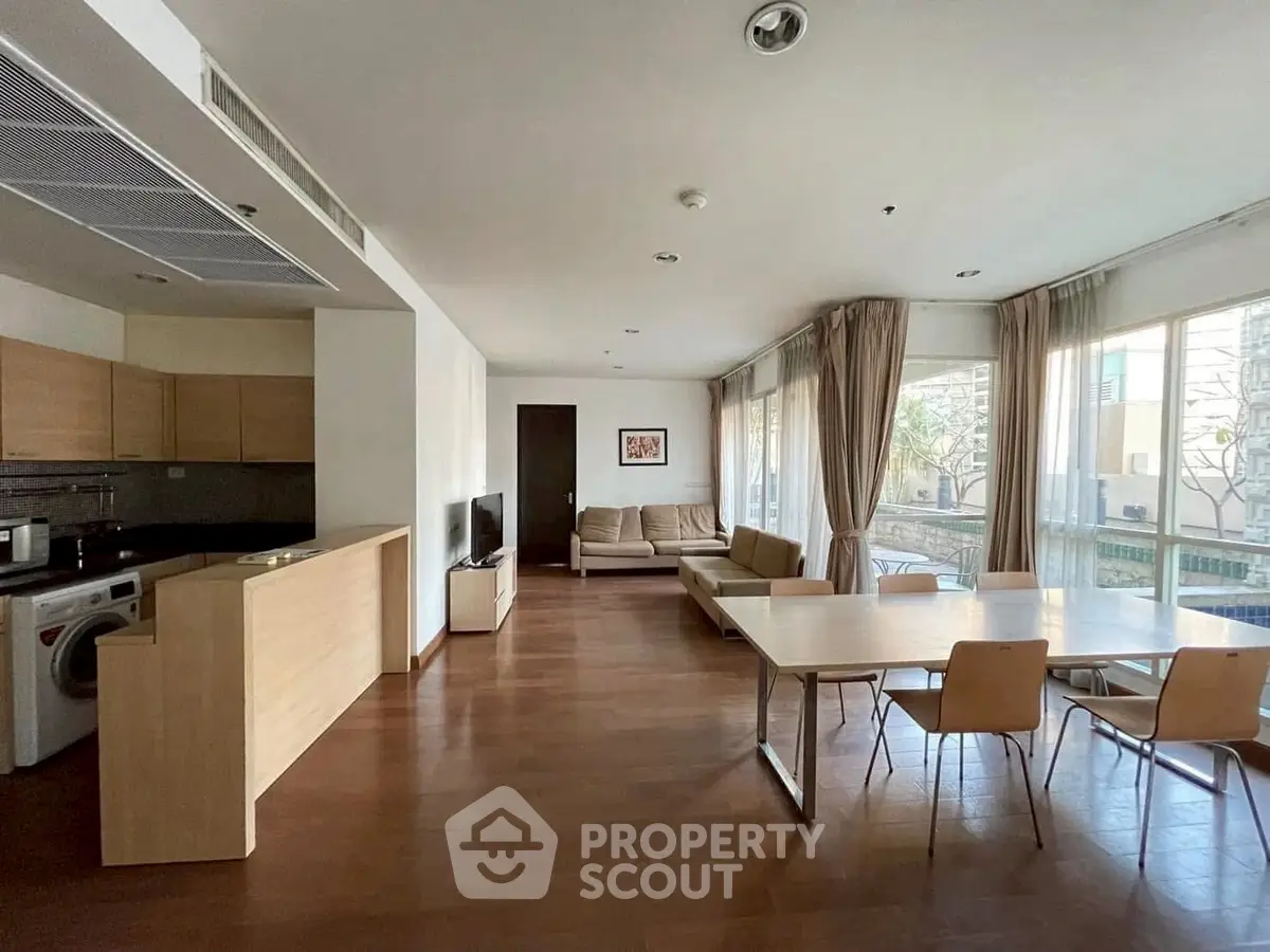 Spacious open-plan living room with dining area and modern kitchen in a bright apartment.