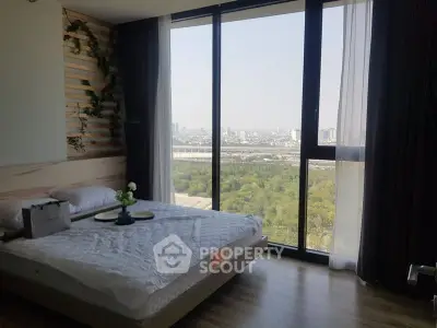 Modern bedroom with large window offering stunning city and park views, featuring elegant decor and natural light.