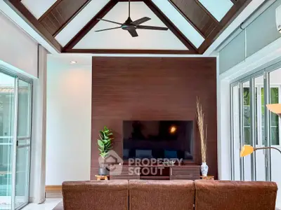Stunning living room with high ceiling and modern decor, featuring a sleek TV setup and large windows.