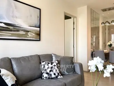 Modern living room with stylish decor and open dining area, featuring elegant furniture and contemporary artwork.