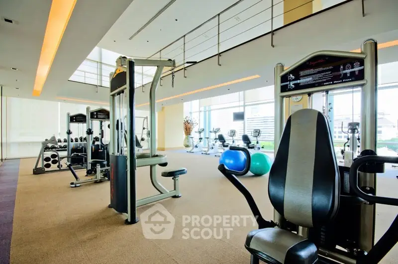 Spacious modern gym with state-of-the-art equipment and natural lighting in luxury residential building.