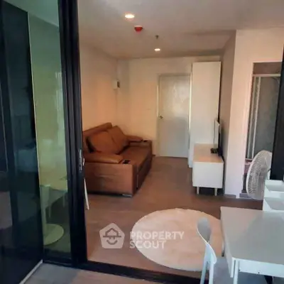 Modern living room with brown sofa and white furniture, open layout design.