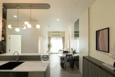 Modern open-layout kitchen and dining area with stylish lighting and contemporary decor.