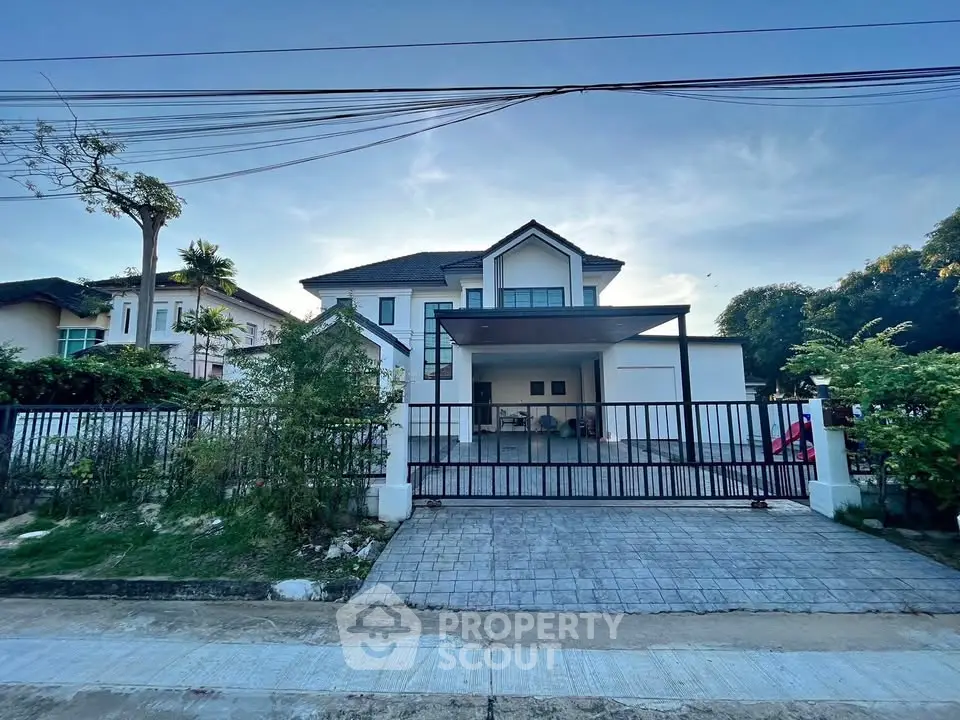 Spacious modern house with gated driveway and lush greenery, perfect for family living.