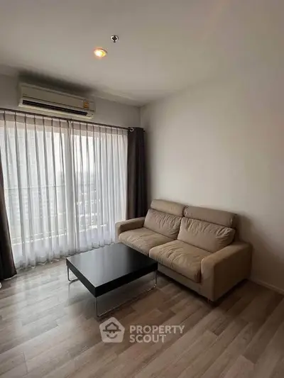 Modern living room with sleek sofa and coffee table, featuring large window with city view.
