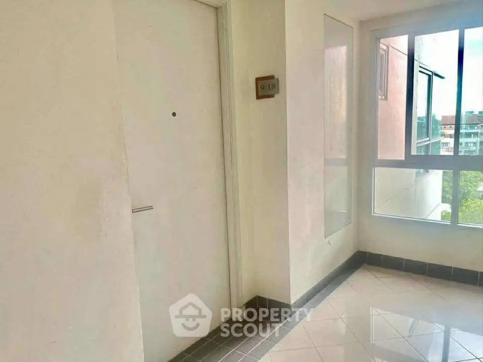 Bright apartment entrance with large window and tiled floor