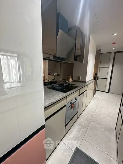 Modern kitchen with sleek cabinetry and built-in oven, featuring a gas stove and ample counter space.