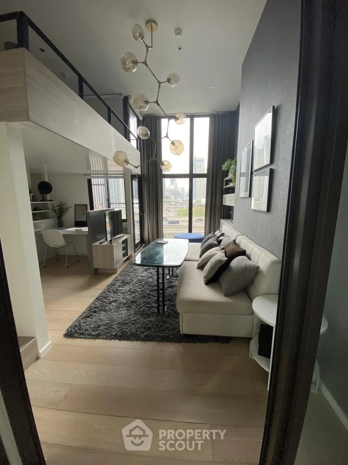 Modern loft-style living room with high ceilings and city view, featuring chic decor and cozy seating area.