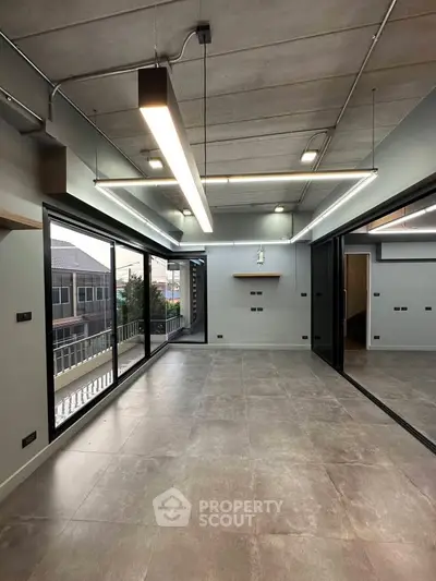 Modern industrial-style living room with large windows and balcony access.