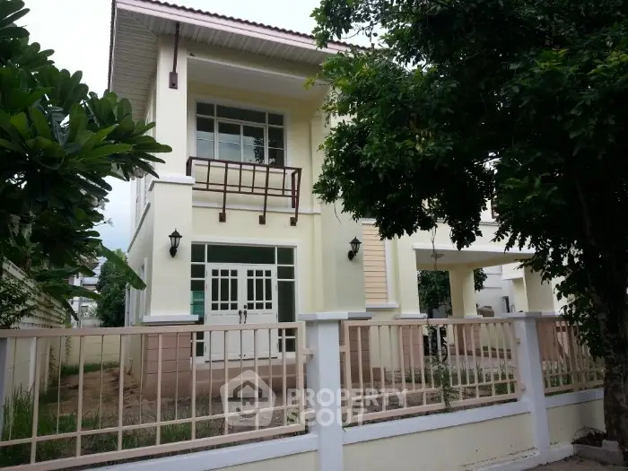 Charming two-story house with balcony and lush greenery, perfect for family living.