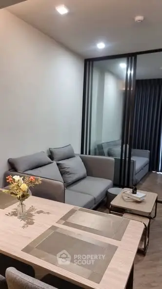 Modern living room with stylish gray sofa and elegant dining area in open layout apartment.