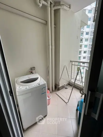 Compact laundry area with washing machine and drying rack in modern apartment balcony.