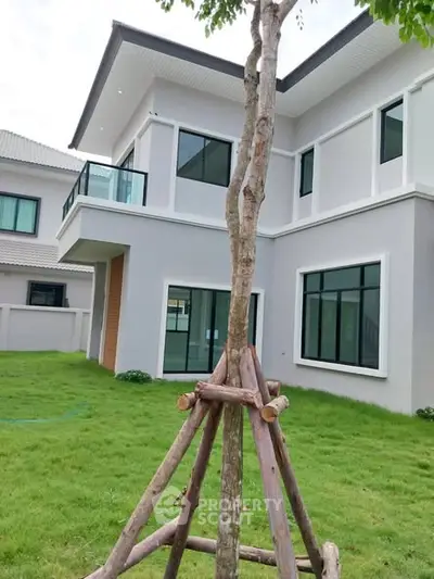 Modern two-story house with large windows and lush green lawn, perfect for family living.