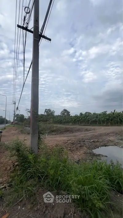 Expansive land plot with lush greenery and potential for development under a cloudy sky.